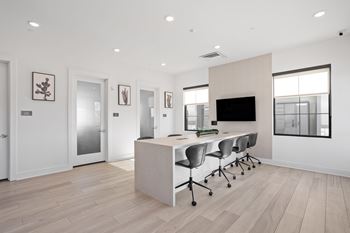 A modern office space with a desk, chairs, and a television.